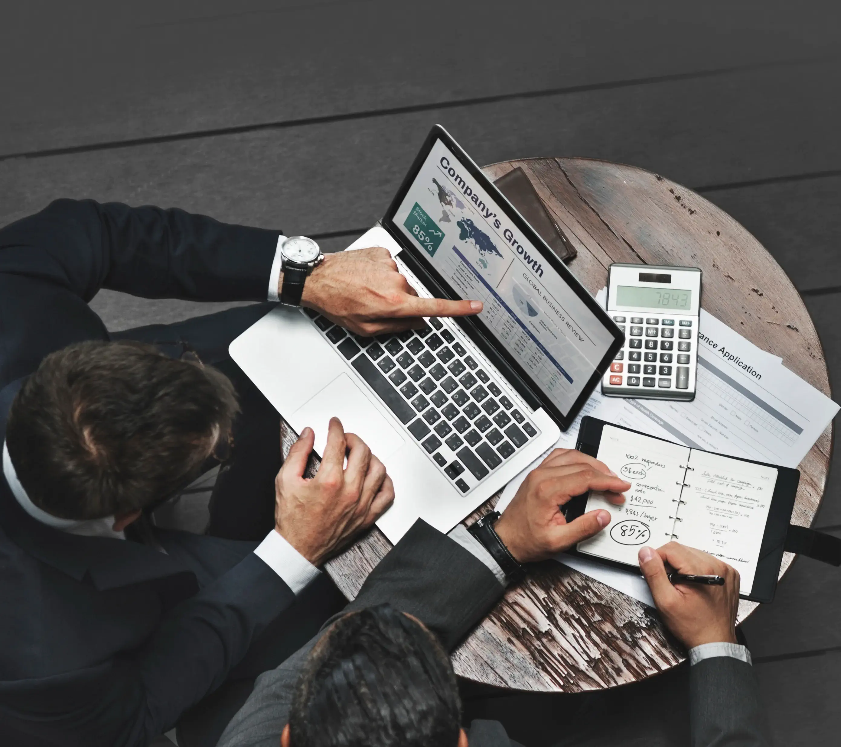 Consultants collaborating on strategic digital transformation plans, with laptops and documents in a modern meeting space.