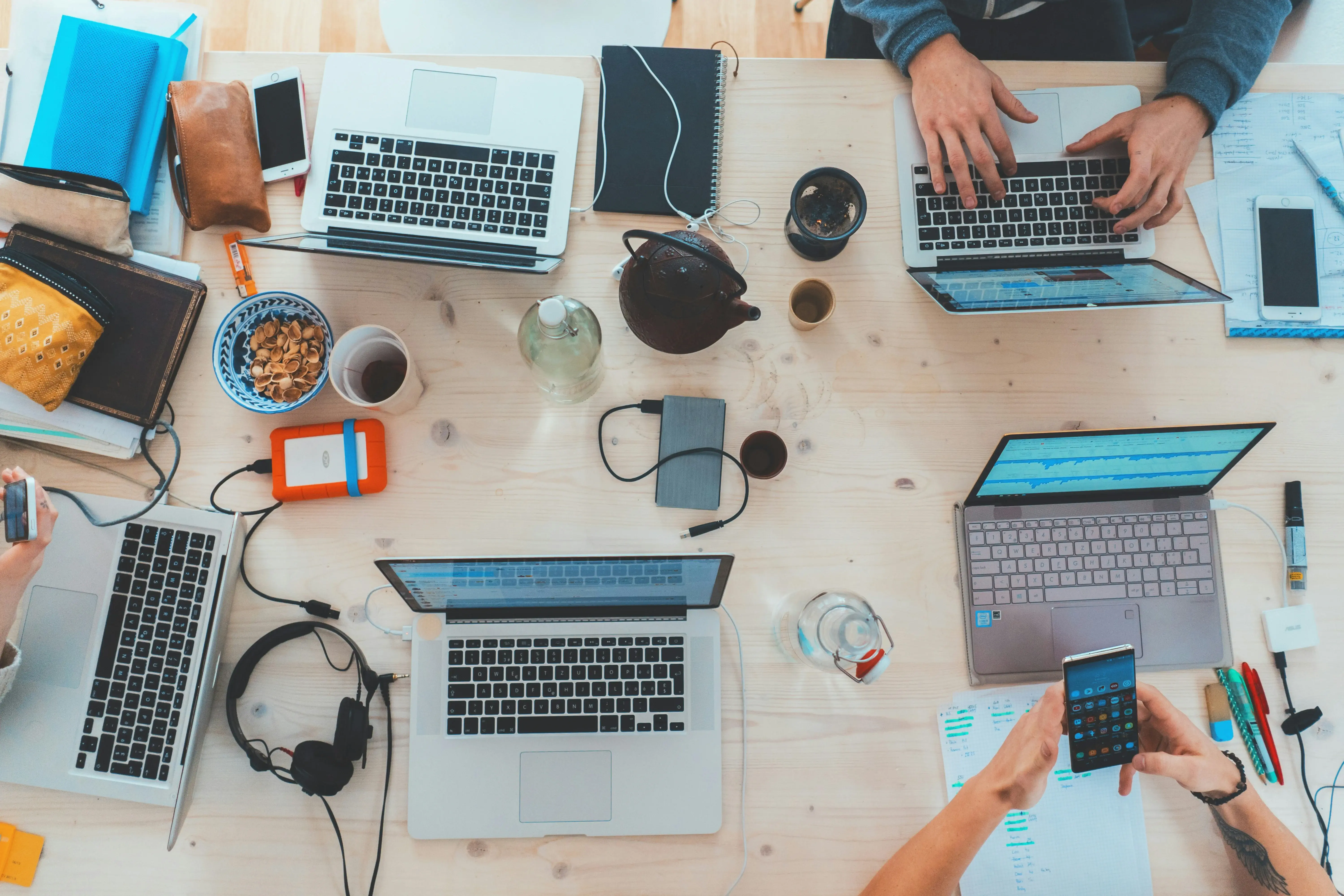 Overhead view of a collaborative tech team working on laptops and mobile devices, symbolizing custom software development and agile teamwork.
