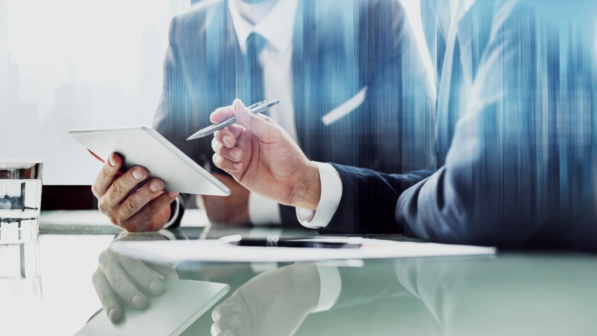 Two business professionals in suits discussing data on a tablet, symbolizing strategic IT consulting and expert guidance.