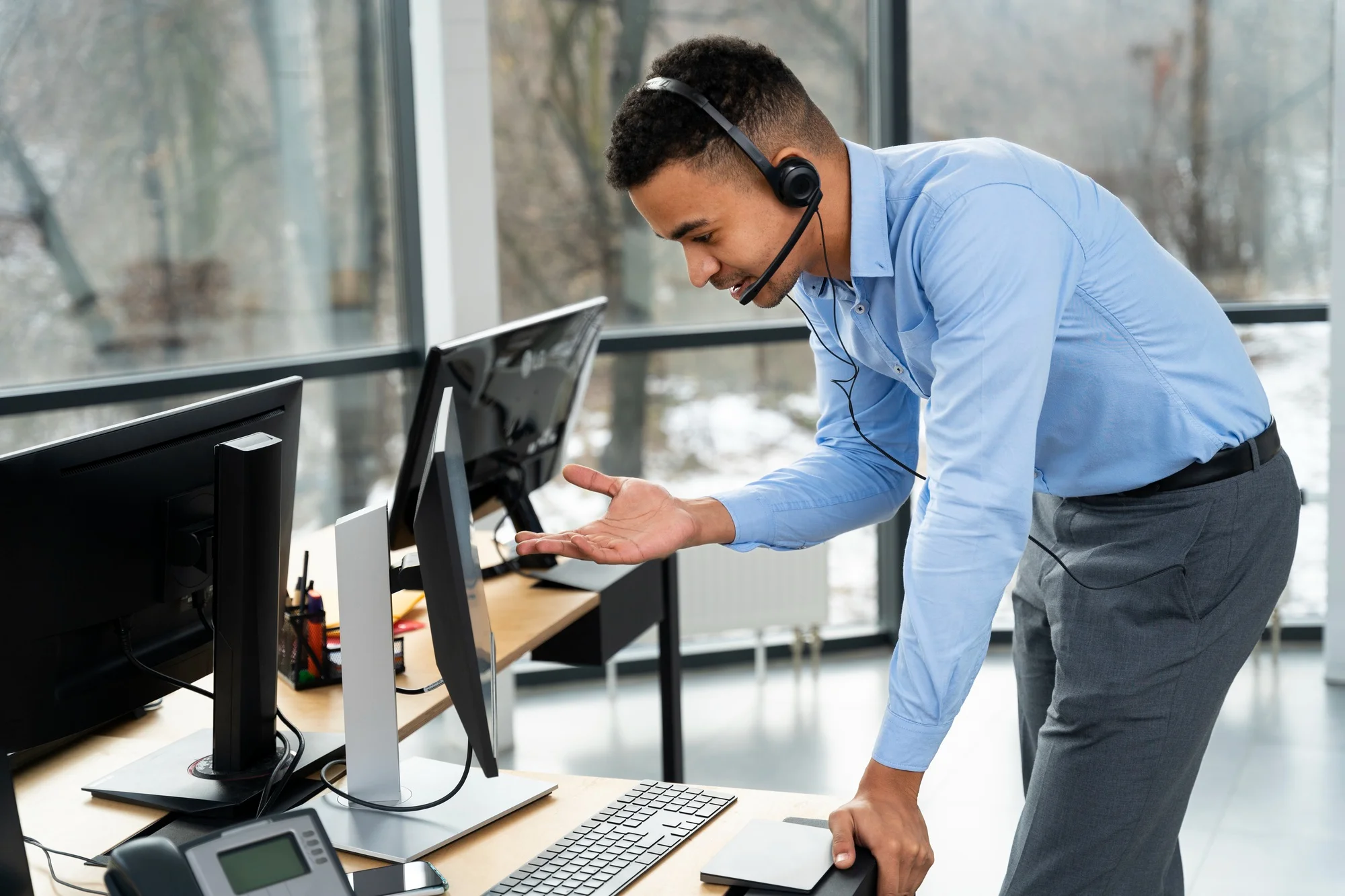 A male IT support professional wearing a headset, assisting at a computer workstation, symbolizing dedicated customer service and technical support.