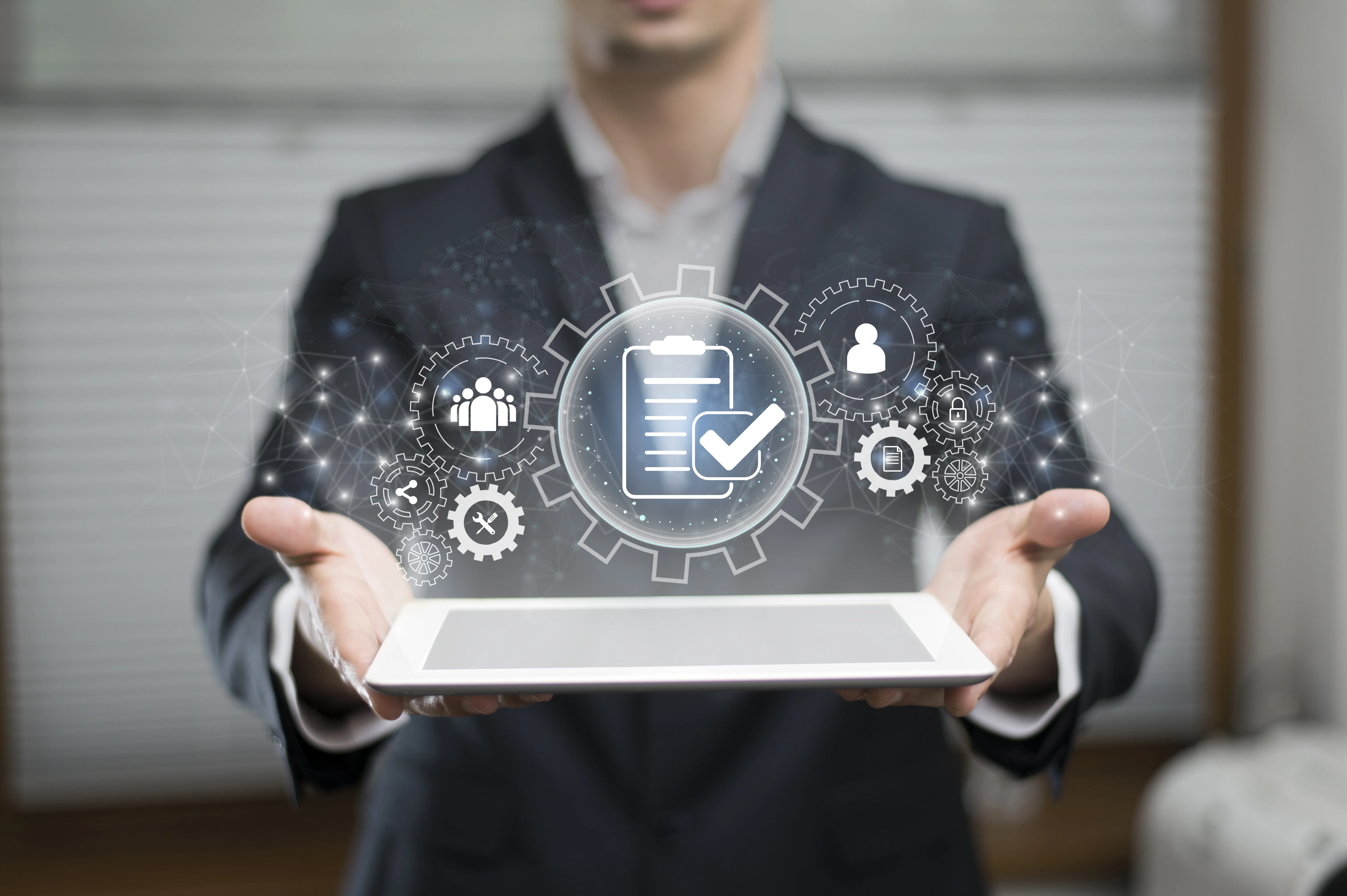 A person in business attire holding a tablet, with a digital overlay showing a large gear icon surrounded by various tech service symbols, representing comprehensive business solutions.